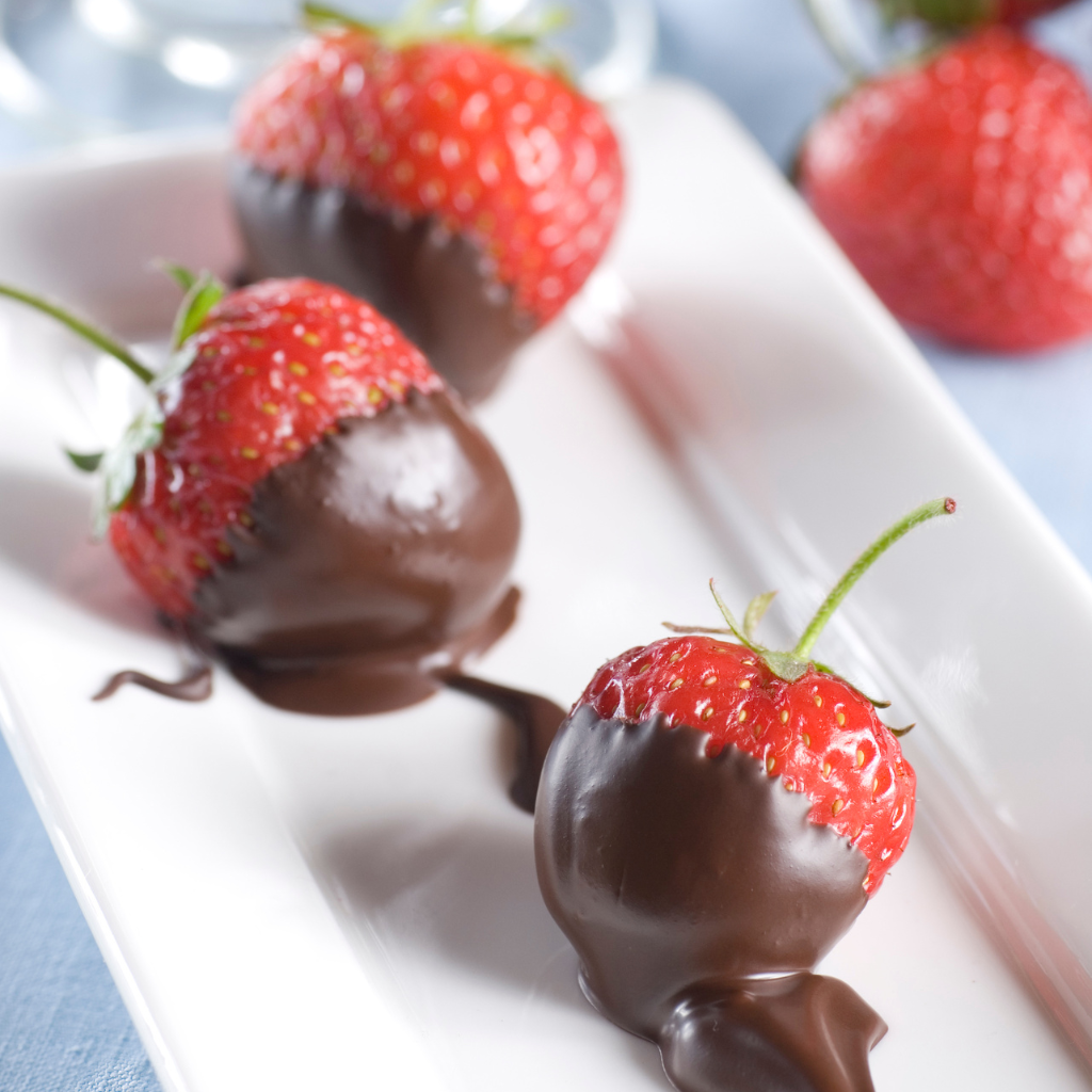 Fresones bañados en chocolate negro sobre plato blanco
