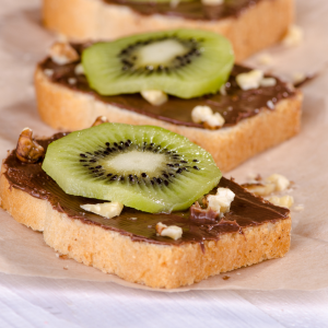 Tosta de pan con crema de cacao, nueces y rodaja de kiwi verde