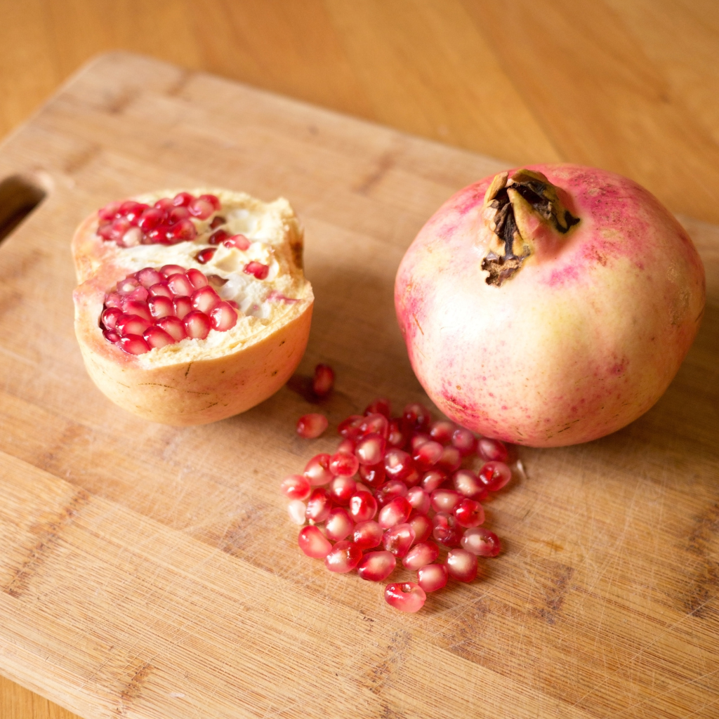granada abierta con granos frescos sobre tabla de madera