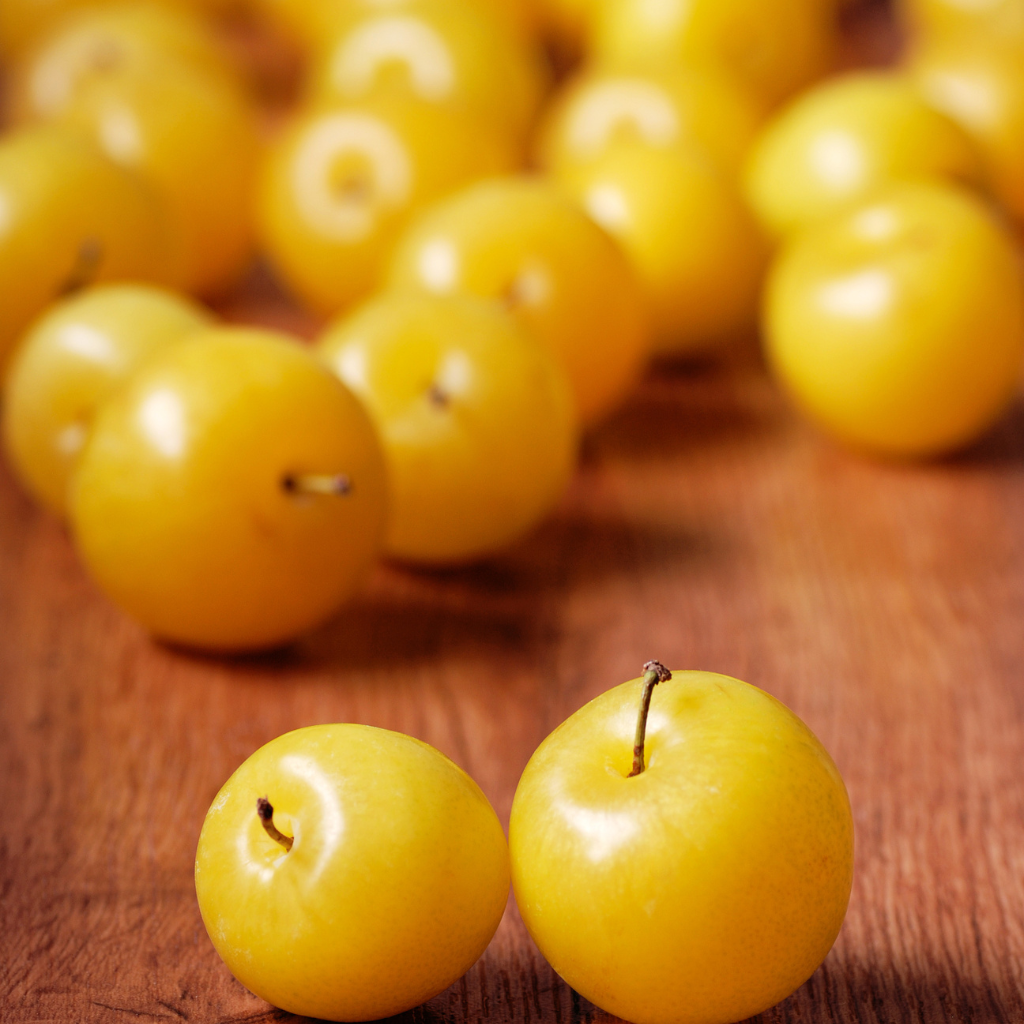 Ciruelas amarillas frescas en mesa de madera