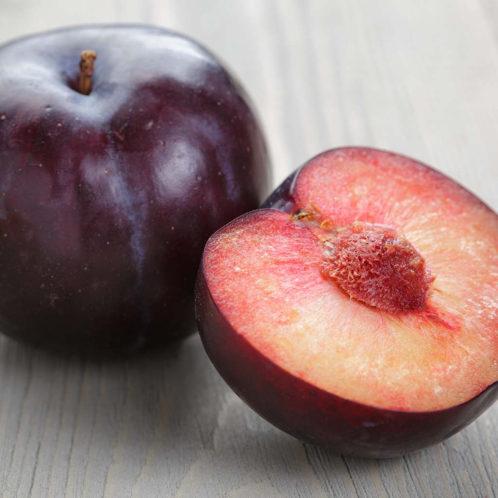 ciruela roja fresca partida mostrando pulpa jugosa