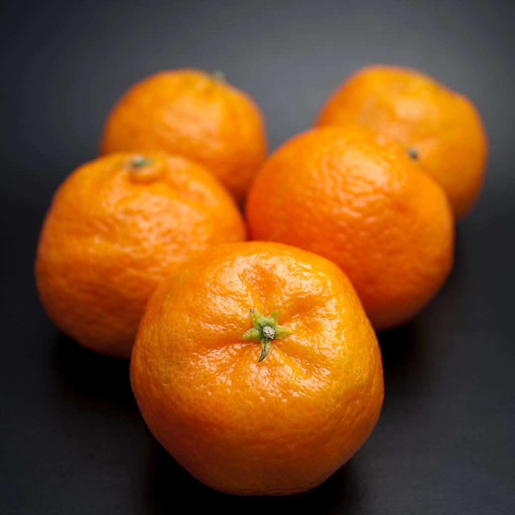 Mandarinas extra frescas con piel brillante sobre fondo oscuro