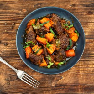Guiso casero con batata, carne y verduras servido en plato hondo