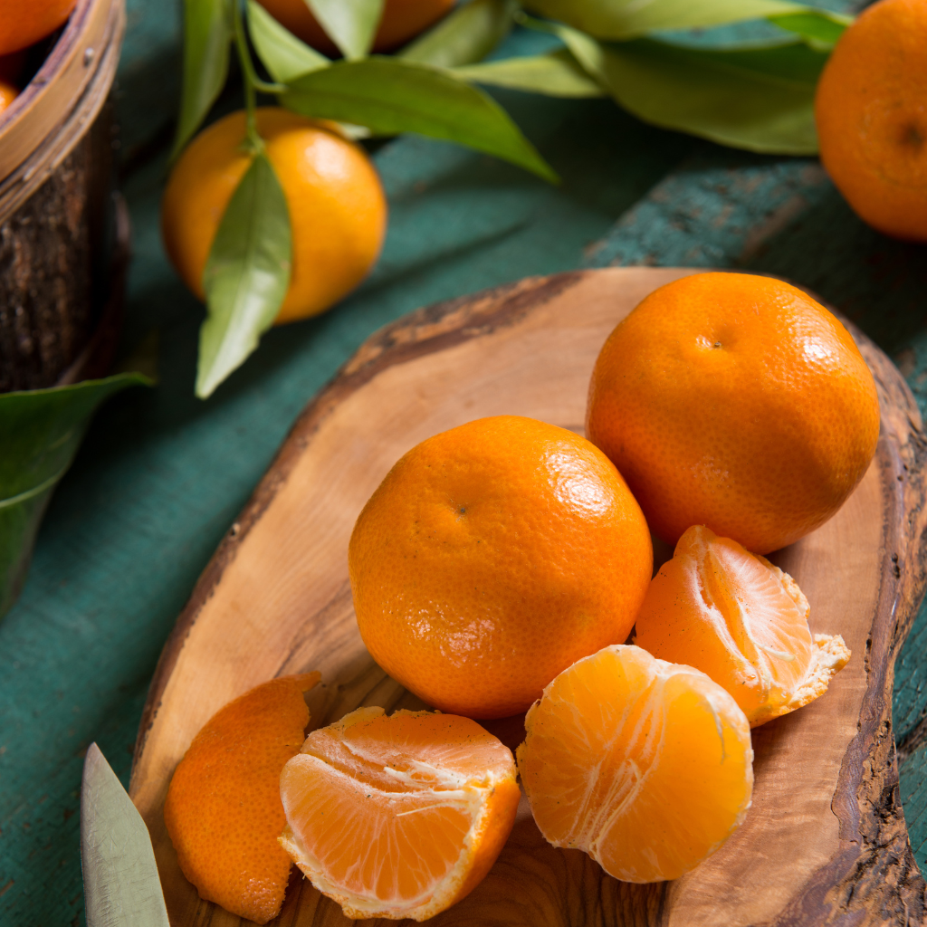 Mandarinas frescas con hoja verde sobre tabla artesanal