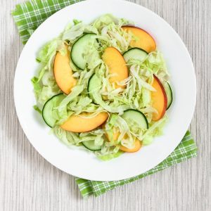 Ensalada ligera de lechuga iceberg, pepino y melocotón fresco