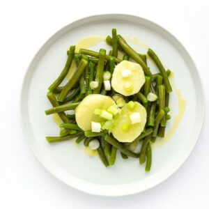 Judías verdes con patata cocida y aliño suave en plato blanco