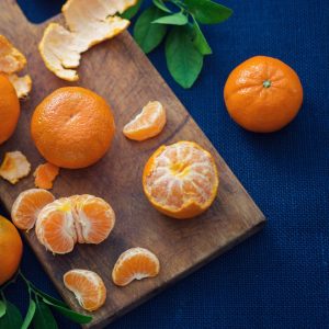 Mandarinas frescas enteras y peladas sobre tabla de madera