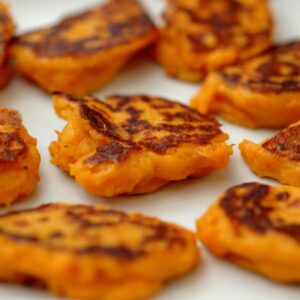 Pancakes de batata caseros dorados sobre plato blanco