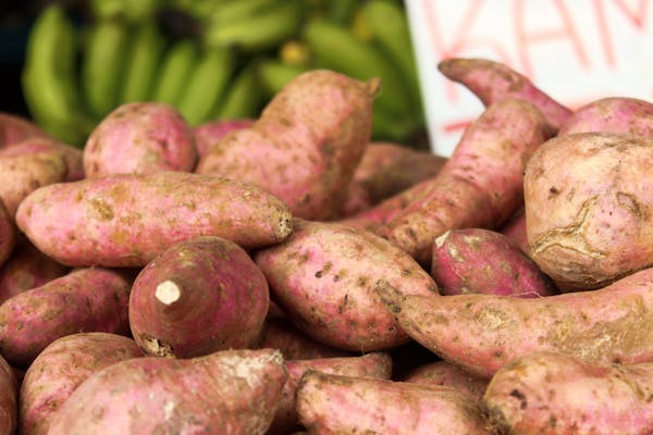 Close-up of freshly harvested sweet potatoes at a market, showcasing their natural textures.
