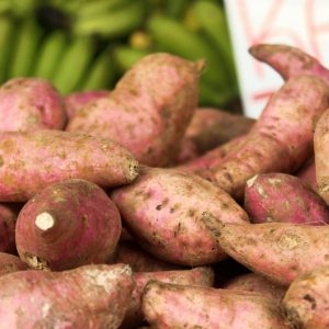 Close-up of freshly harvested sweet potatoes at a market, showcasing their natural textures.