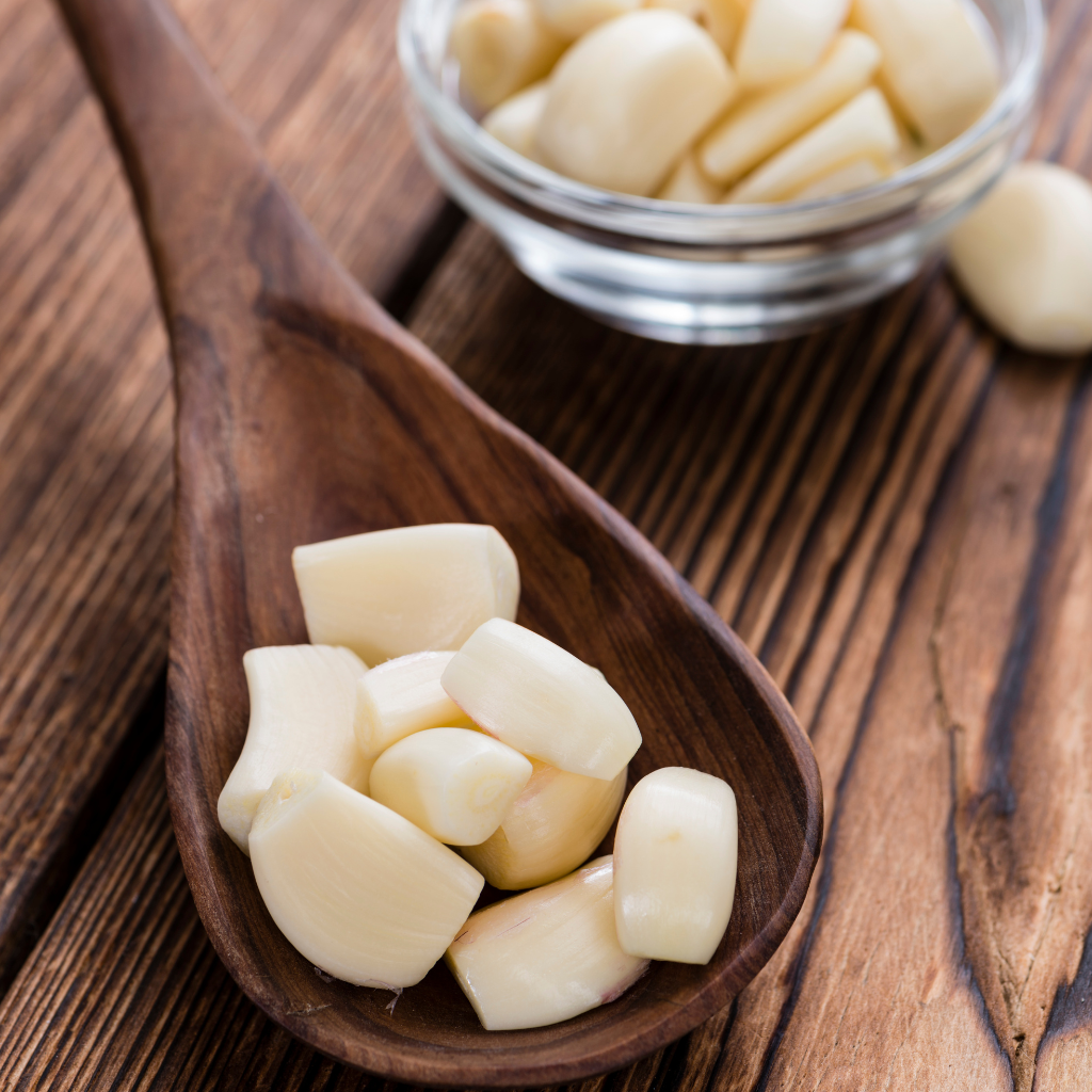 Ajos pelados frescos listos para cocinar sobre cuchara de madera