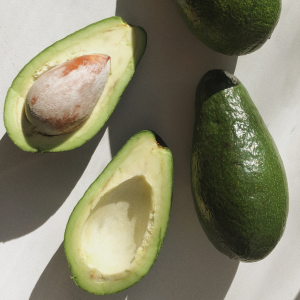 Aguacates Bacon enteros y cortados sobre fondo claro.