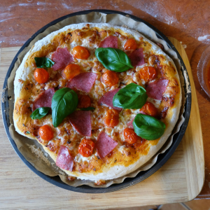 Pizza casera con tomate cherry pera y hojas de albahaca