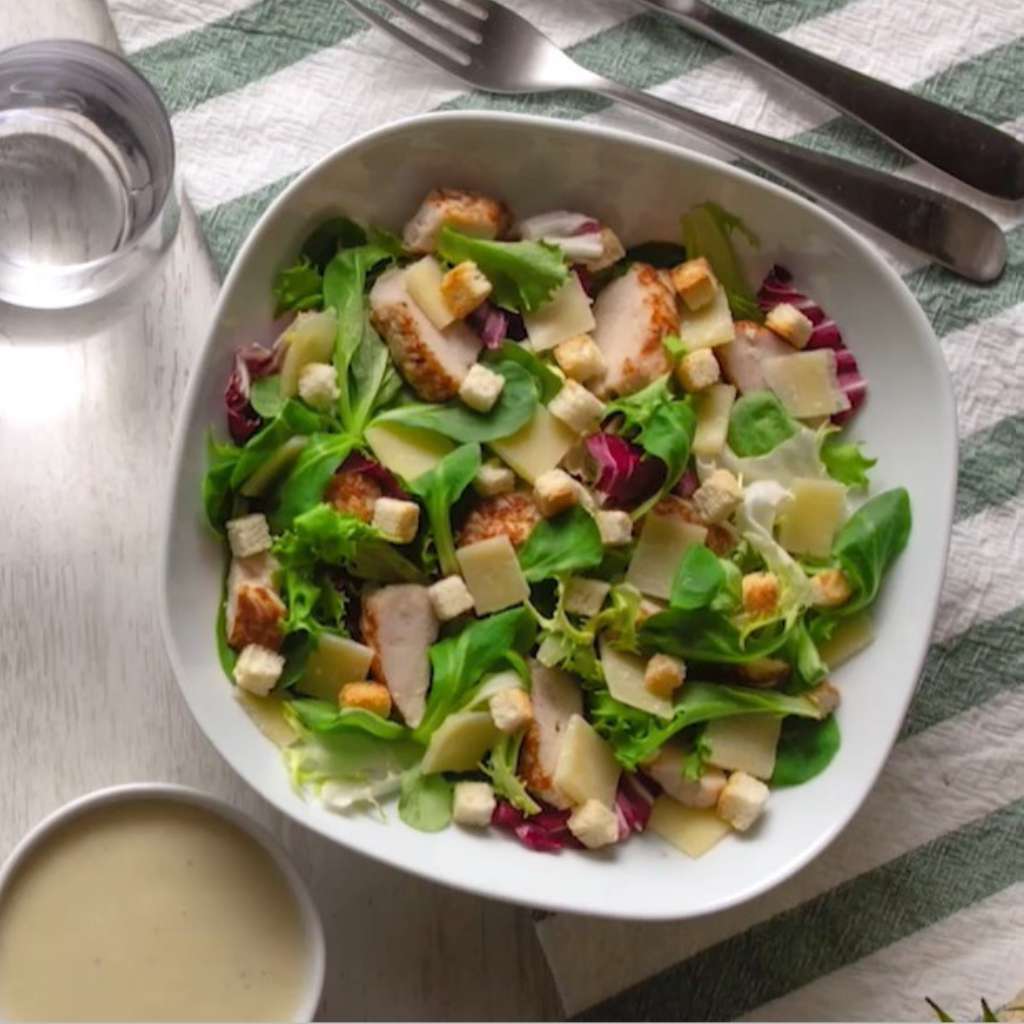 ensalada césar con pollo braseado, parmesano y picatostes