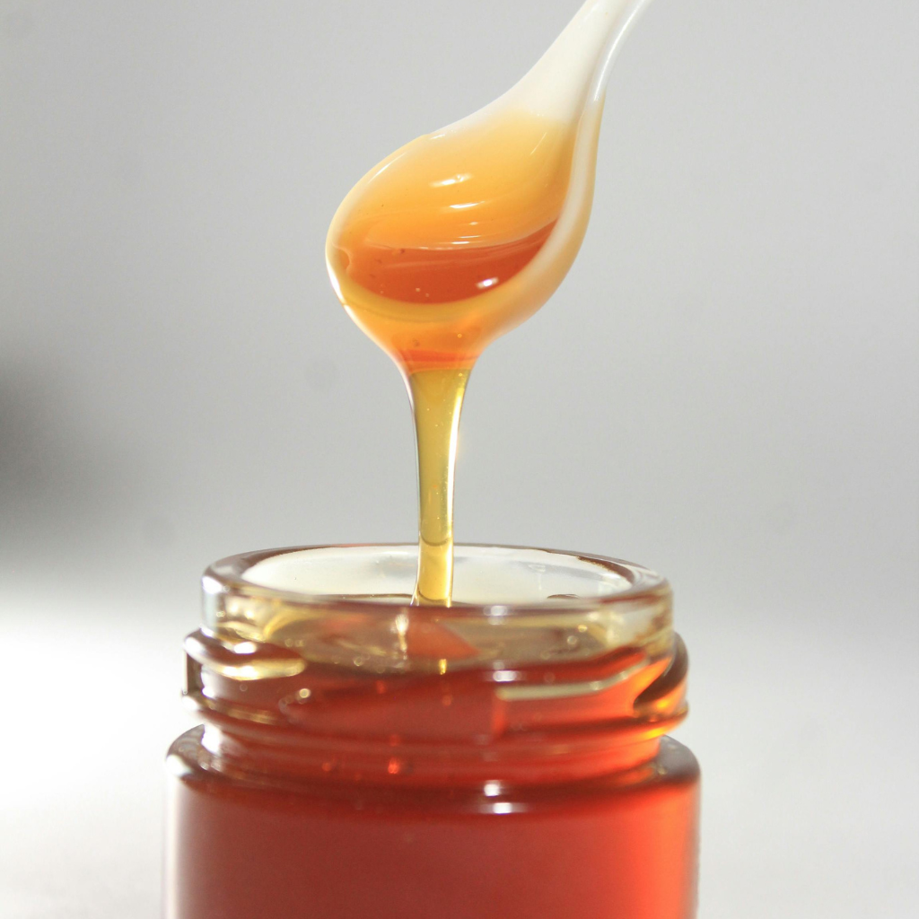 Cucharada de miel de mil flores cayendo sobre tarro