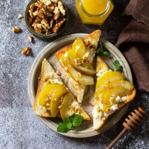 Tostas con pera, queso y nueces peladas sobre plato