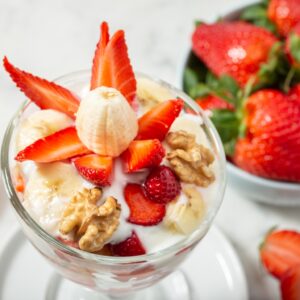 Yogur con fresas, plátano y nueces peladas en copa